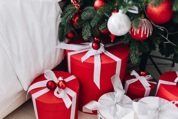 Muchos regalos de Navidad bellamente envueltos en rojo y blanco debajo del árbol de Navidad