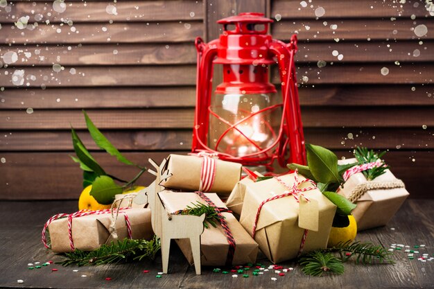 Muchos regalos de Navidad decorados y una antigua lámpara de aceite vintage sobre madera