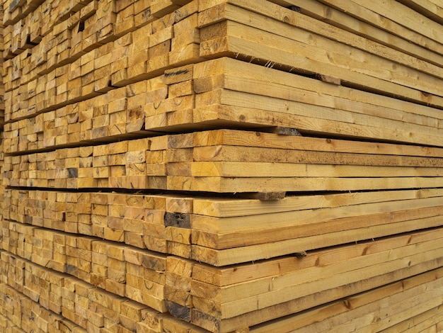 Muchos tablones apilados uno encima del otro en el almacén. Madera para su posterior uso en la construcción.