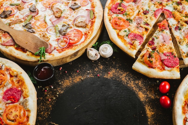 Muchos tipos de pizzas sabrosas sobre fondo negro. Flatlay. copia espacio