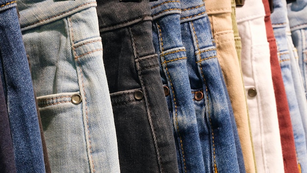 Muchos vaqueros colgando en arack fila de pantalones vaqueros denim pendiendo en el armario concepto de comprar vender compras y vaqueros moda