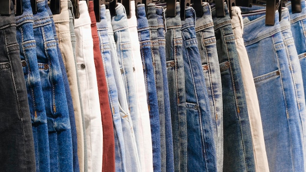 Muchos vaqueros colgando en arack fila de pantalones vaqueros denim pendiendo en el armario concepto de comprar vender compras y vaqueros moda