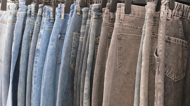 Muchos vaqueros colgando en arack fila de pantalones vaqueros denim pendiendo en el armario concepto de comprar vender compras y vaqueros moda