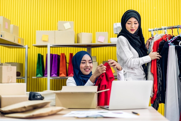 Muçulmano duas mulheres asiáticas freelancer sme negócios on-line trabalho de compras e ordem de lista de verificação com caixa de papelão na mesa em casa Conceito de entrega e envio on-line de negócios