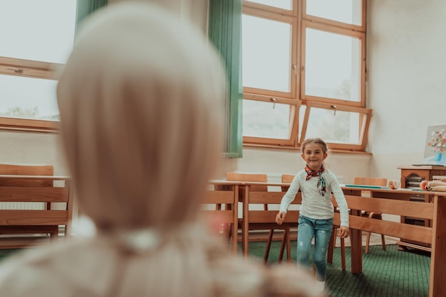 Muçulmano hijab o professor abraça a garotinha na escola Foco seletivo Foto de alta qualidade