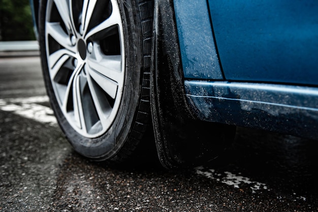 Mudgaurd do carro, mudflap na roda dianteira do estacionamento azul no asfalto molhado.