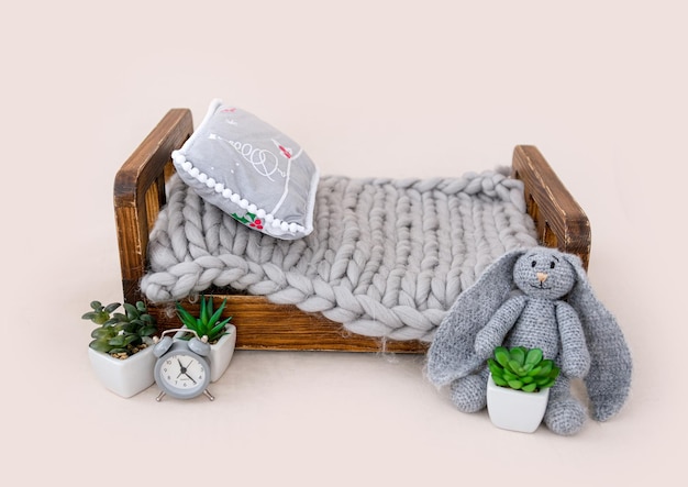 Muebles de estudio para bebés recién nacidos cama pequeña con piel decorada con plantas de flores y conejito de punto. Hermoso lugar para sesión de fotos de estudio de niños pequeños