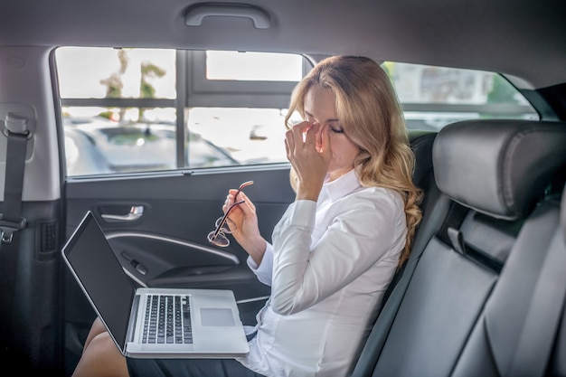 Müde. Blonde Geschäftsfrau, die in einem Auto sitzt und müde schaut