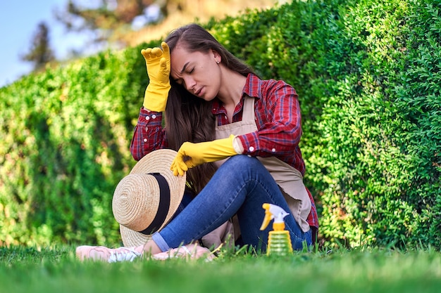 Müde Gärtnerin, die im Gras sitzt