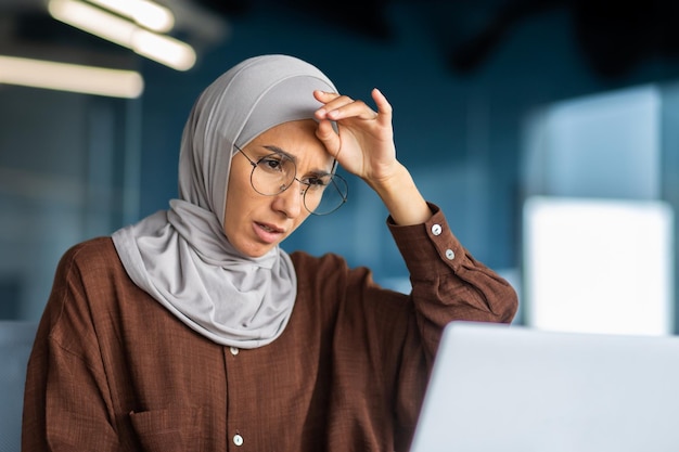 Müde Geschäftsfrau, die am Arbeitsplatz im Büro arbeitet, muslimische Frau mit Hijab ist schwer krank