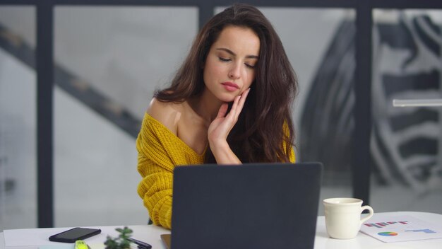 Müde Geschäftsfrau streckt drinnen die Arme aus Überarbeitetes Mädchen gähnt in der Nähe des Laptops