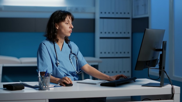 Foto müde, gestresste medizinische krankenschwester, die am schreibtisch steht und über stunden bei der gesundheitsbehandlung arbeitet und patientenrezepte während des kontrollbesuchstermins eingibt. erschöpfter assistent, der die krankheitsdiagnose analysiert