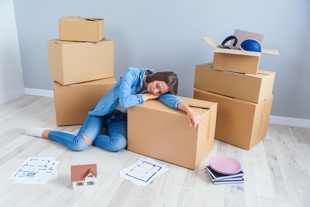 Müde junge Frau, die eine Pause vom Packen macht