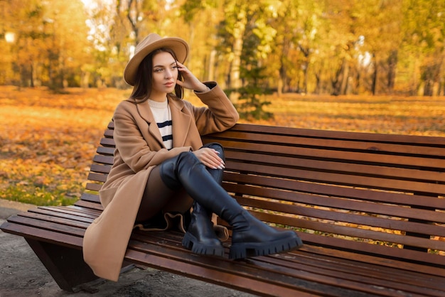 Müde oder depressive junge Frau, die im Herbstpark ihren Kopf berührt Das Mädchen leidet unter schrecklichen Kopfschmerzen, fühlt sich einsam gestresst oder unglücklich und hat Probleme