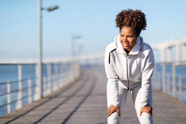 Müde sportliche schwarze Frau, die nach dem aktiven Training im Freien Luft holt