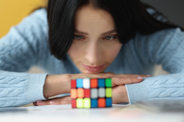 Müde traurige Frau sieht sich nicht gesammelten Rubik-Würfel an, der wichtige Entscheidungen trifft