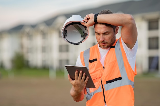 Foto müder bauarbeiter auf der baustelle, bauleiter oder ingenieur im helm-außenbau