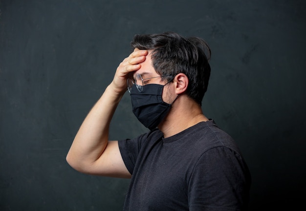 Müder Brunet-Mann in der schwarzen Gesichtsmaske an der dunklen Wand