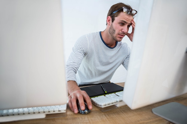 Müder Mann, der an Computer in einem hellen Büro arbeitet