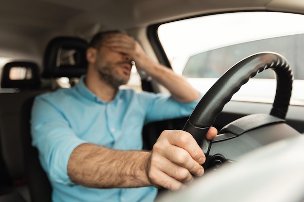 Müder Mann sitzt im Auto im Stau