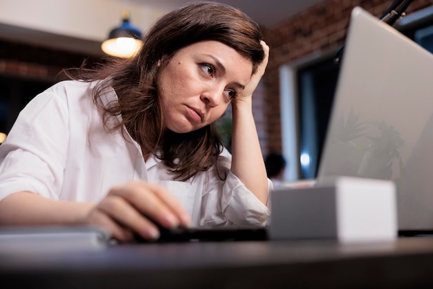 Müder Mitarbeiter eines Unternehmens, der am Schreibtisch im Büroarbeitsbereich sitzt und aufgrund von Überstunden unter Müdigkeit leidet. Erschöpfter Leiharbeiter, der an Burnout-Syndrom und Migräne leidet.