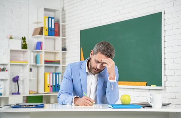 Müder Schullehrer im Klassenzimmer an der Tafel