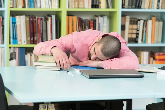 Müder Student, der in der Bibliothek schläft