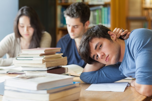 Müder Student, der in der Bibliothek stillsteht