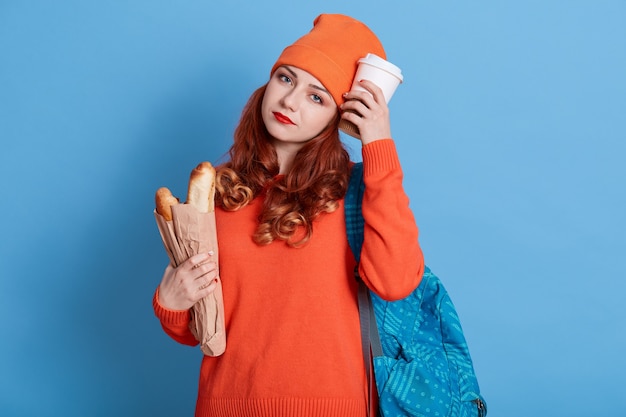 Müder Student, der nach den Vorlesungen einen Snack isst, schaut mit traurigem Ausdruck in die Kamera und ist nach dem Lernen müde