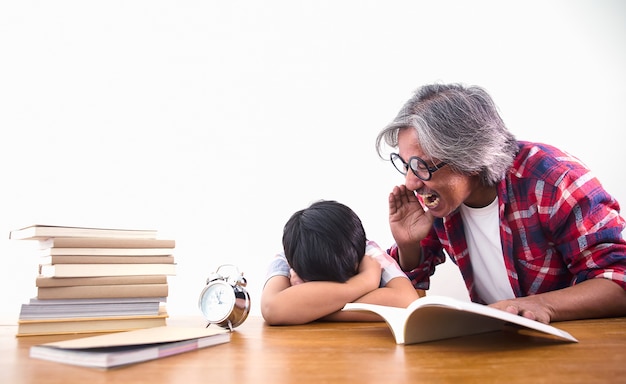 Müder und gelangweilter junge, der unter den büchern im klassenzimmer schläft