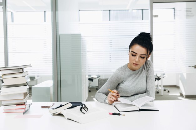 Müdes Mädchen arbeitet mit Büchern in der Bibliothek