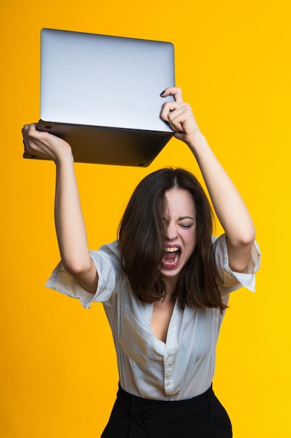 Müdigkeit bei der Arbeit. Junge Frau will Laptop zertrümmern