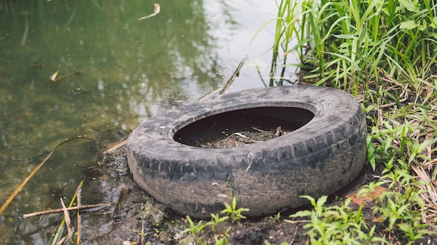 Müll im Fluss oder See das Rad liegt neben dem Wasser Das Konzept der Umweltverschmutzung Umweltprobleme der Natur