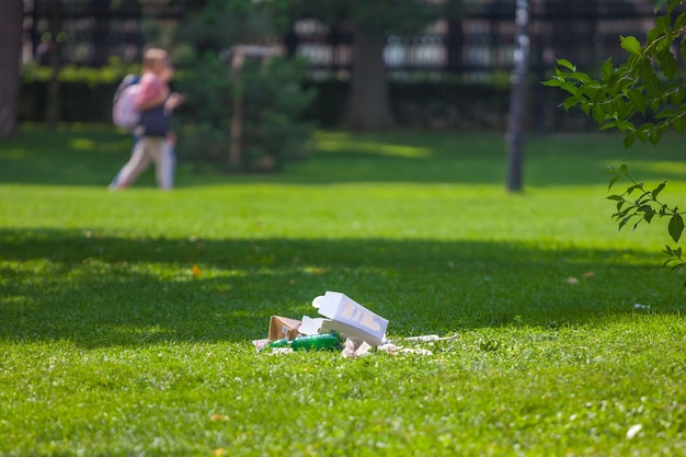 Müll in einem öffentlichen Park auf grünem Gras.