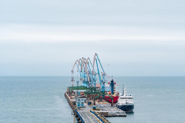 Muelle de carga con grúas portuarias y barcos amarrados contra el fondo del mar abierto