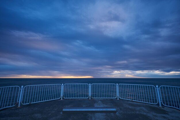 Muelle desierto con un cielo dramático sobre un mar tormentoso y oscuro al amanecer.