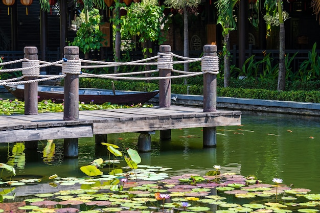 Muelle de madera en un estanque en un jardín tropical en Danang, Vietnam. Concepto de viajes y naturaleza.