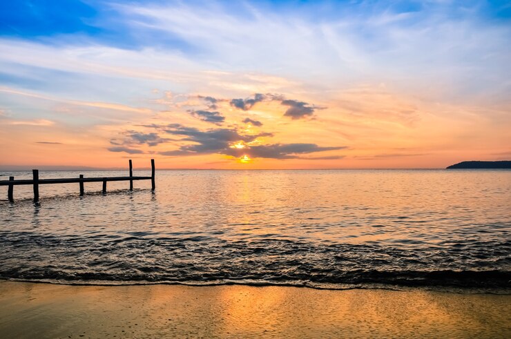 Muelle de madera ir al mar con amanecer.