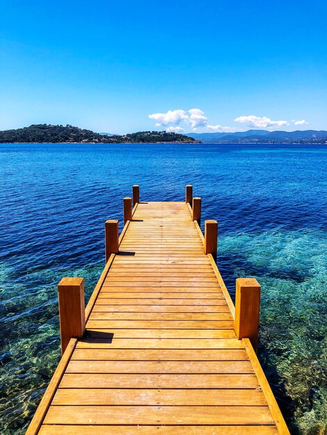 Foto el muelle de madera que conduce al muelle sobre el mar contra el cielo azul