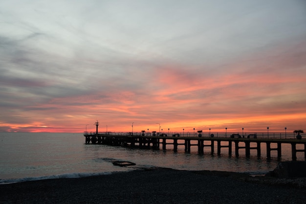 Muelle de pesca en el océano con un colorido y dorado amanecer en la playa del océano y un colorido espectacular