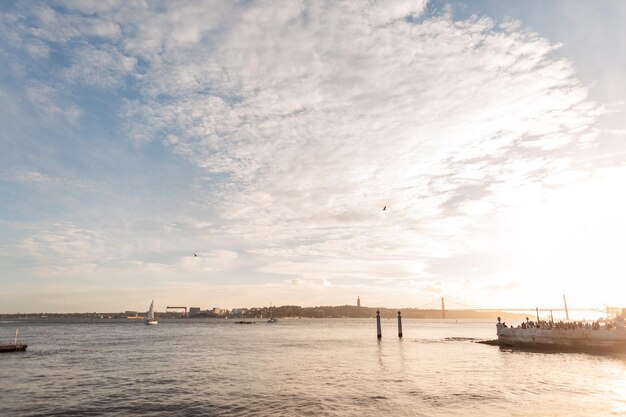 Muelle de playa junto al mar con nubes en un atardecer dorado en Lisboa Portugal