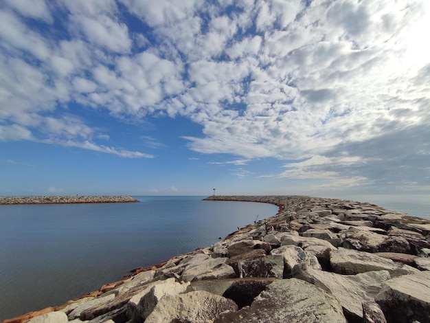 Un muelle rocoso con un cielo azul y nubes encima