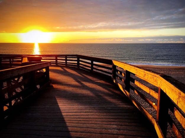 Muelle sobre la playa contra el mar durante la puesta de sol