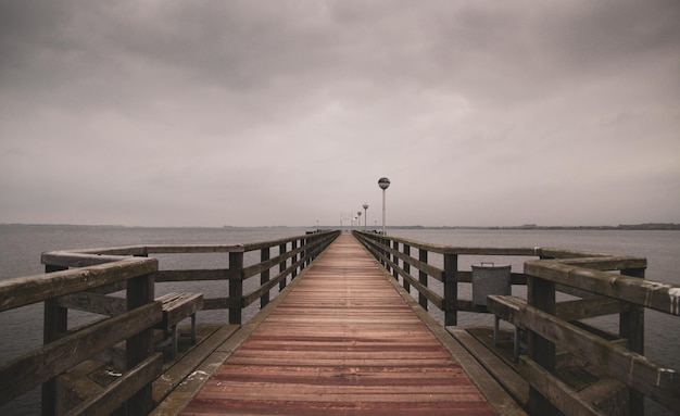 El muelle vacío que conduce al muelle sobre el mar contra el cielo