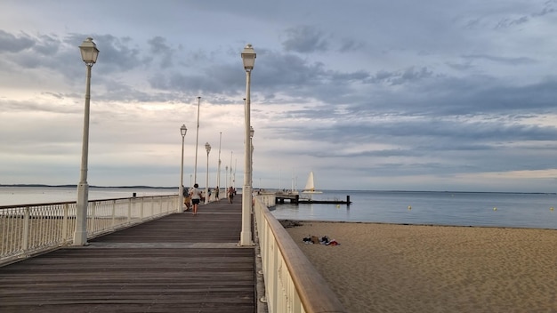 Un muelle con un velero a lo lejos.