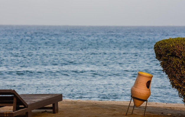 Mülleimer aus Ton und ein Strauch mit einer Sonnenliege am Roten Meer