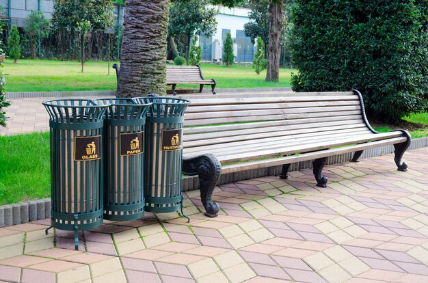 Foto mülleimer zum sortieren von müll in einem stadtpark neben einer bank.