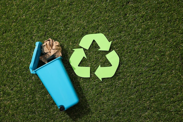 Foto mülltonne mit dem symbol des recyclingmülls auf dem gras