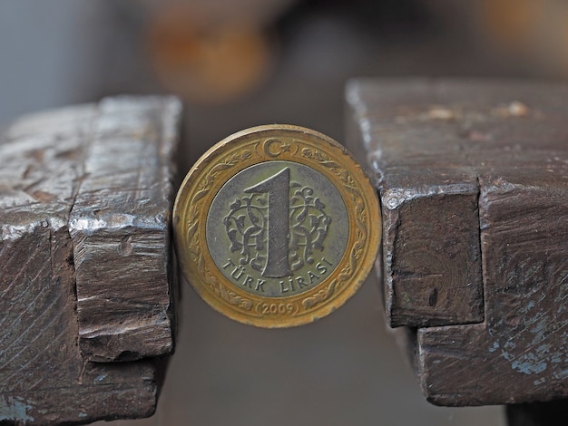 Münze eine türkische Lira in einen Schraubstock eingespannt. Das Konzept der finanziellen und wirtschaftlichen Probleme.
