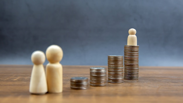 Münzen gestapelt in einer Graphform mit Holzpuppe zum Geldsparen